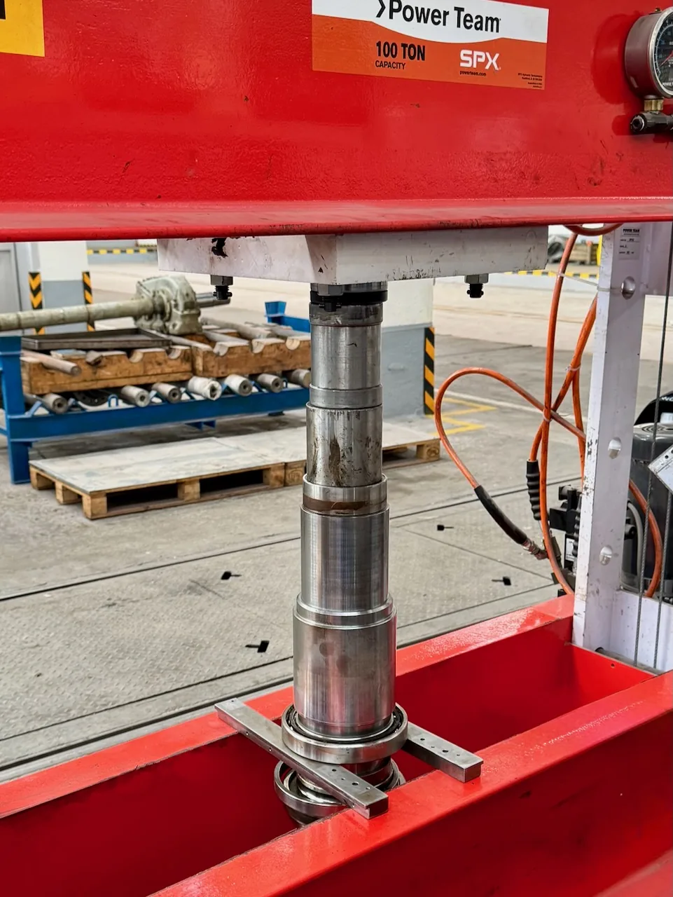 Vřetenový hřídel v hydraulickém lisu při demontáži ložiska.